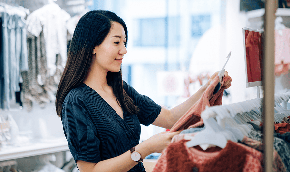 A person holds an item of clothing at a clothing store