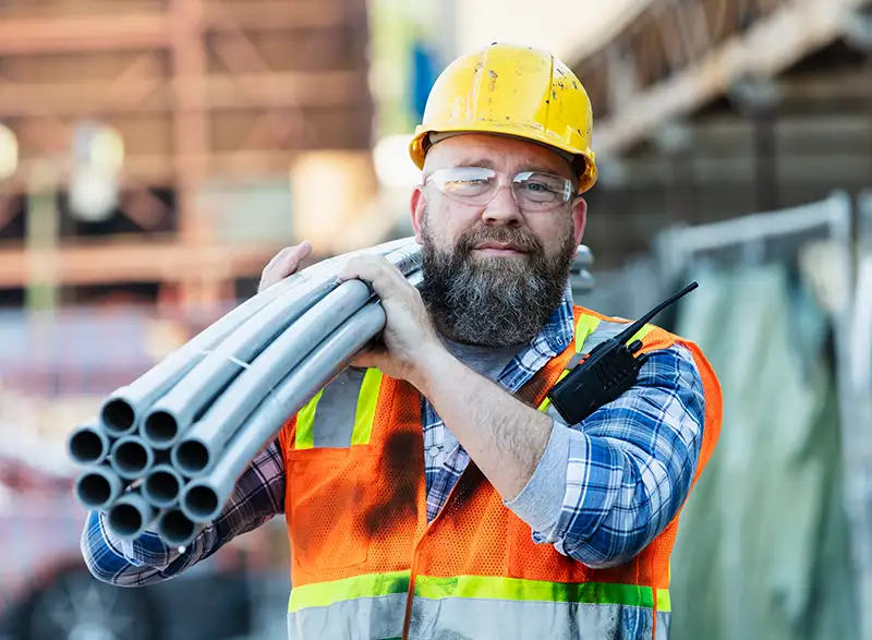 construction worker carrying steel tubes on construction site