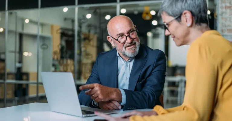 man and women in a business office looking at laptop talking