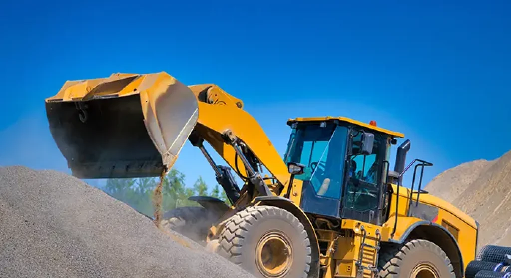 Heavy equipment loader driving up pile of gravel